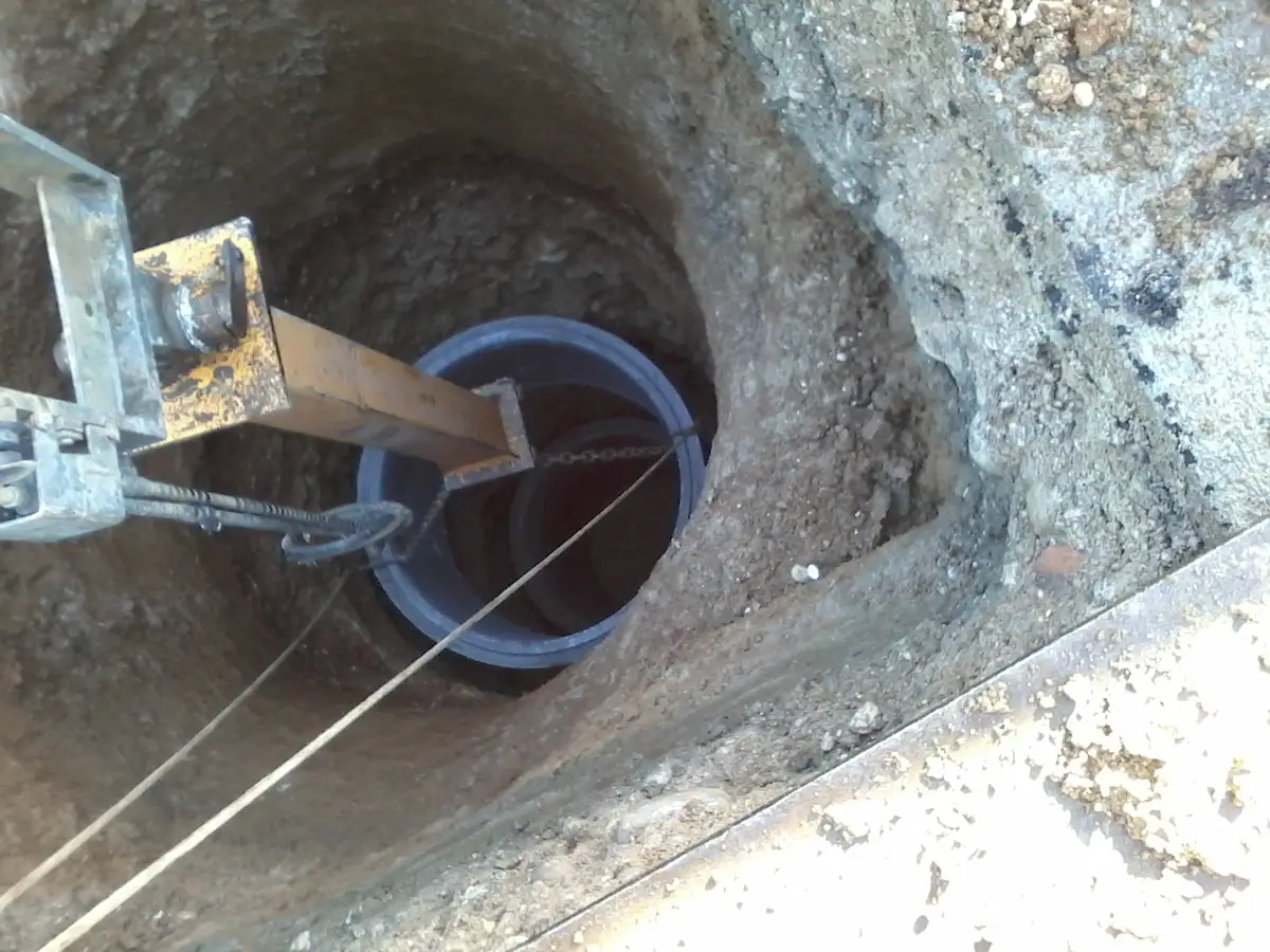 Pozzo autoaffondante in fase di calo: anello in discesa nello scavo con attrezzatura di sollevamento e guida