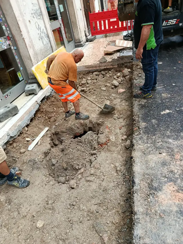 Scavo manuale attorno a un pozzo in una via del centro storico